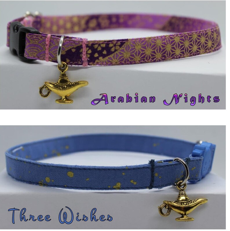 K&ouml;nnte beinhalten: Zwei Katzenhalsb&auml;nder mit goldenen Flaschengeist-Anh&auml;ngern. Das erste Halsband ist lila mit einem goldenen Blumenmuster und dem Text "Arabian Nights". Das zweite Halsband ist blau mit goldenen Punkten und dem Text "Three Wishes".