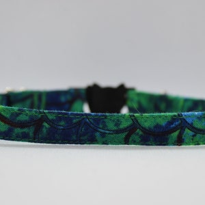 May include: A green and blue patterned cat collar with a black buckle.