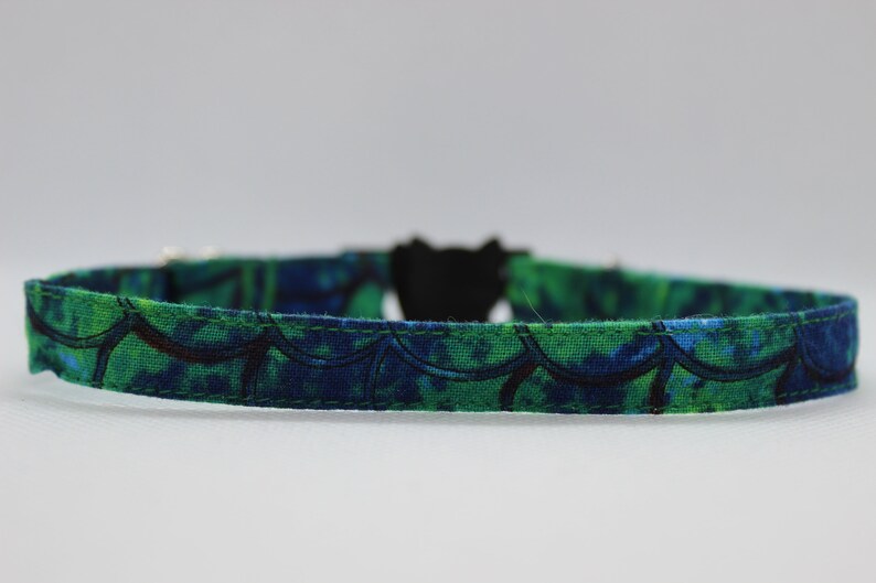 May include: A green and blue patterned cat collar with a black buckle.