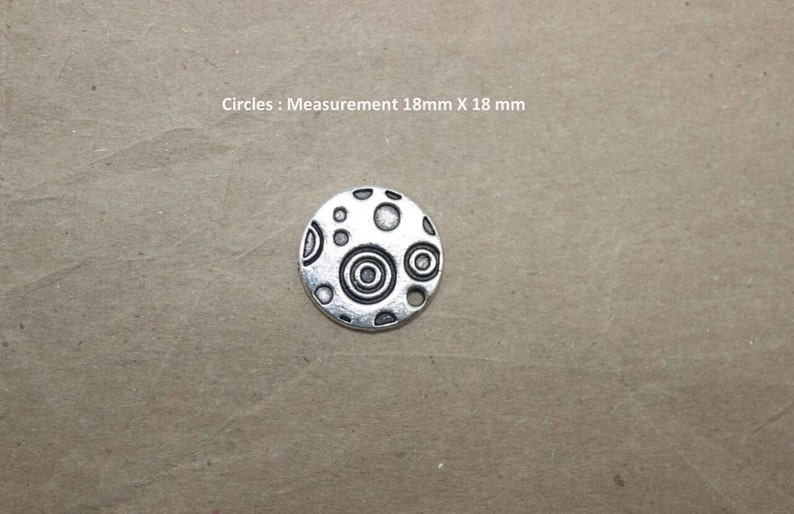Puede incluir: Encanto de plata con un dise&ntilde;o circular que presenta c&iacute;rculos conc&eacute;ntricos y puntos. El encanto mide 18 mm de di&aacute;metro. C&iacute;rculos: Medida 18 mm X 18 mm