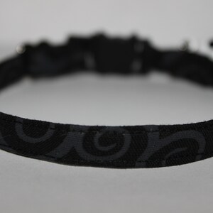May include: Black cat collar with a swirl pattern.