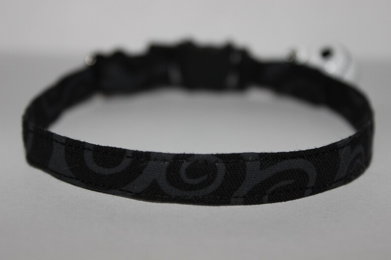 May include: Black cat collar with a swirl pattern.