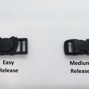 May include: Two black plastic buckles for straps. The buckle on the left has a cat design and the text "Easy Release". The buckle on the right is a standard buckle with the text "Medium Release".