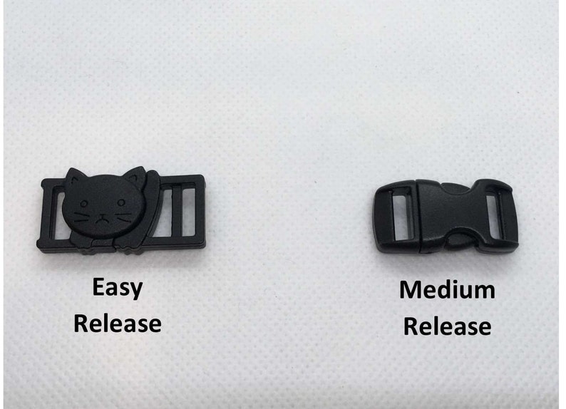 May include: Two black plastic buckles for straps. The buckle on the left has a cat design and the text "Easy Release". The buckle on the right is a standard buckle with the text "Medium Release".