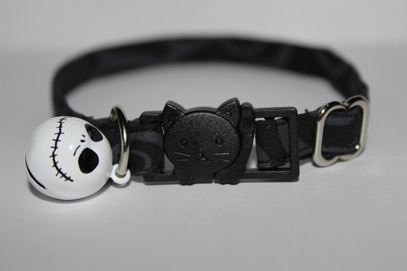 May include: Black cat collar with a black cat buckle and a white bell with a black Jack Skellington face.