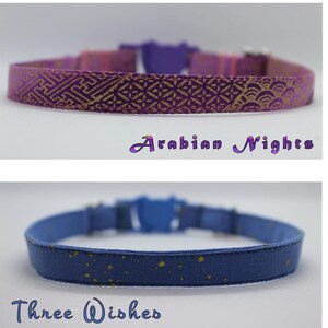 K&ouml;nnte beinhalten: Zwei Katzenhalsb&auml;nder, eines lila mit einem goldenen geometrischen Muster und dem Text "Arabian Nights" und eines blauen mit goldenen Punkten und dem Text "Three Wishes".