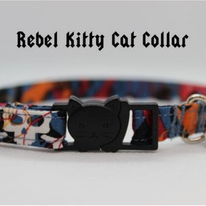 May include: A colorful cat collar with a black cat charm and a silver bell. The collar is made of fabric with a blue, orange, and white pattern. The text "Rebel Kitty Cat Collar" is displayed above the collar.
