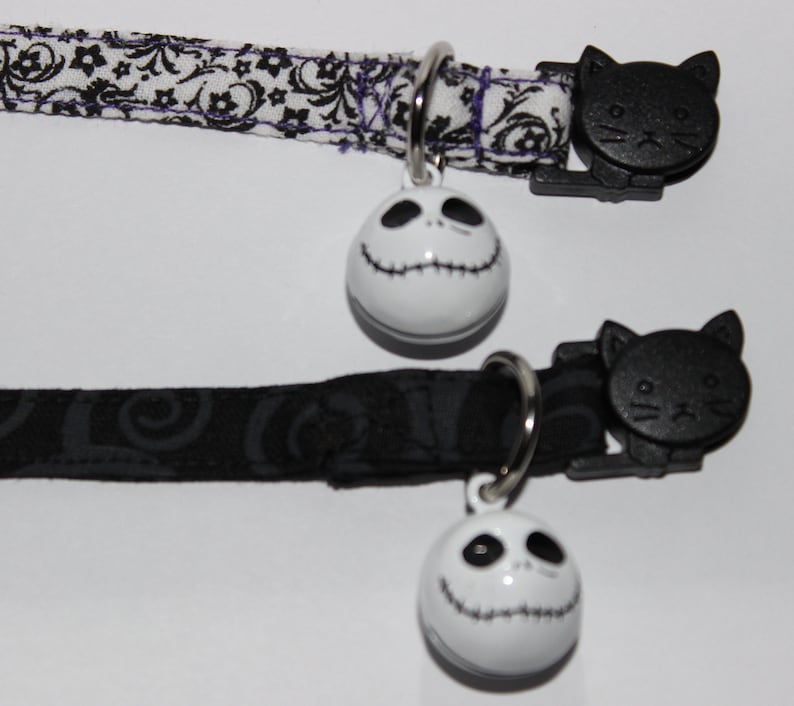 May include: Two black cat collars with a white Jack Skellington bell charm. The collars are made of black and white patterned fabric.