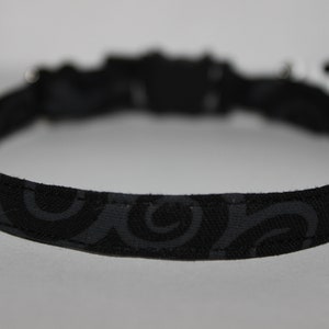 May include: Black cat collar with a swirl pattern.