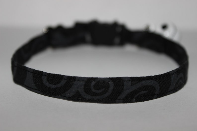 May include: Black cat collar with a swirl pattern.