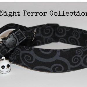 May include: Black cat collar with a grey swirl pattern and a white Jack Skellington bell charm. The collar has a black plastic buckle with a cat face on it.  Night Terror Collection.