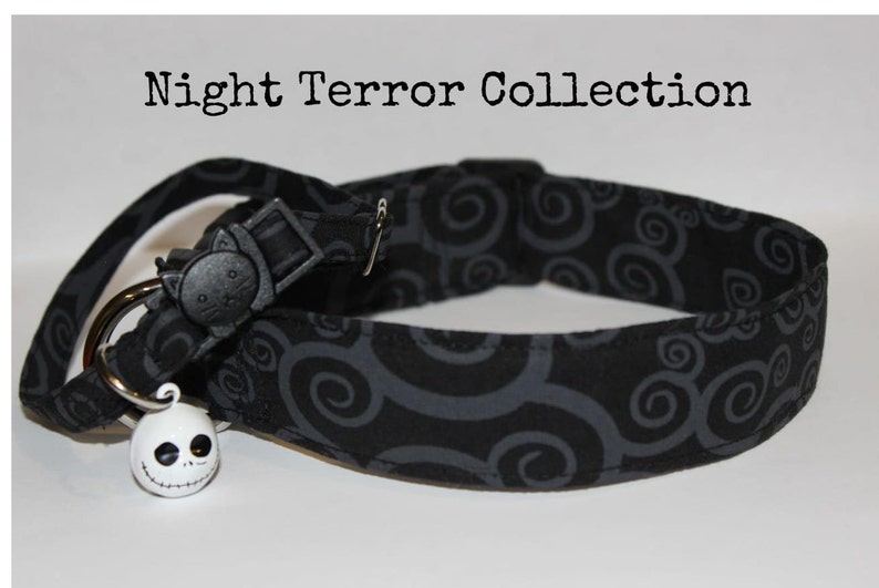 May include: Black cat collar with a gray swirl pattern and a white Jack Skellington bell charm. The collar has a black plastic buckle with a cat face on it.  Night Terror Collection.