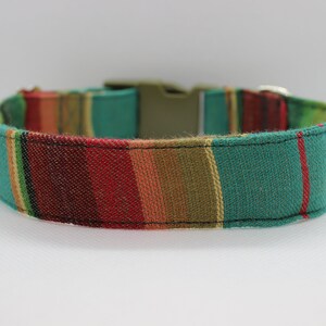 Puede incluir: Un collar de perro a rayas de colores con un patr&oacute;n verde, rojo, amarillo y marr&oacute;n. El collar tiene un cierre de hebilla.