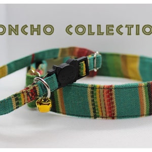 Puede incluir: Un collar para gato a rayas verdes, amarillas, rojas y blancas con una hebilla de seguridad negra y una campanilla dorada. El collar forma parte de una "PONCHO COLLECTION".