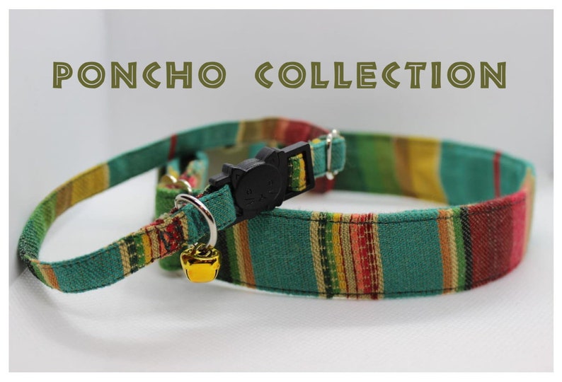 Puede incluir: Un collar para gato a rayas verdes, amarillas, rojas y blancas con una hebilla de seguridad negra y una campanilla dorada. El collar forma parte de una "PONCHO COLLECTION".