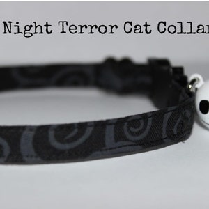 May include: Black cat collar with a gray swirl pattern and a white Jack Skellington bell charm.  "Night Terror Cat Collar" is written above the collar.