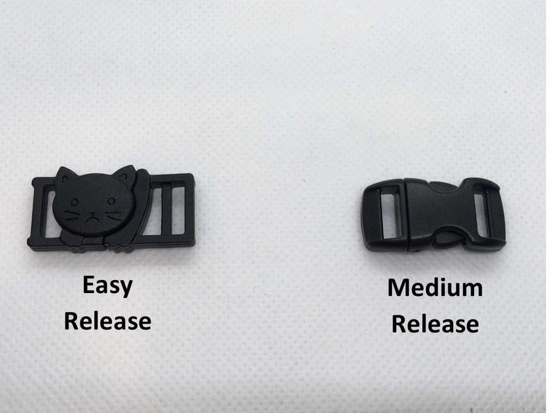 Op de afbeelding: Twee zwarte plastic gespen, een met een kattenontwerp en de tekst "Easy Release" en de andere met de tekst "Medium Release".
