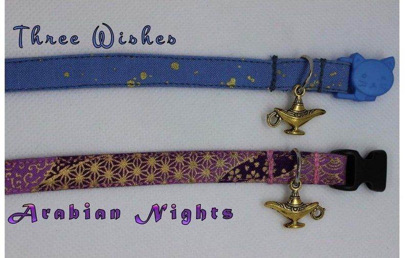 K&ouml;nnte beinhalten: Zwei Katzenhalsb&auml;nder mit einem goldenen Dschinnenlampen-Anh&auml;nger. Das obere Halsband ist blau mit goldenen Glitzer und tr&auml;gt die Aufschrift "Three Wishes". Das untere Halsband ist lila mit goldenen Glitzer und tr&auml;gt die Aufschrift "Arabian Nights".