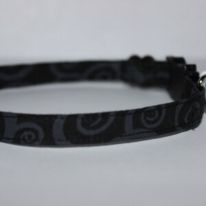 May include: Black cat collar with a white Jack Skellington bell charm. The collar has a black and gray swirl pattern.