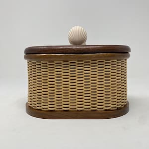 May include: Oval woven wicker box with a wooden lid and a white seashell knob.