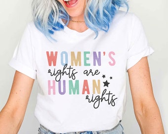 May include: A white t-shirt with the text "WOMEN'S rights are HUMAN rights" printed in colorful letters. The text is in a playful font with stars.