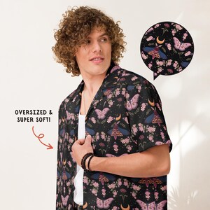 May include: A black short-sleeve button-down shirt featuring a repeating pattern of moths, crescent moons, and pink flowers. The shirt includes a text graphic that reads OVERSIZED & SUPER SOFT! and a circular inset showing the detailed print.
