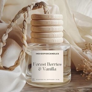 Könnte beinhalten: Ein klarer Glas-Duftöldiffusor mit einem Holzdeckel und einem geflochtenen Seilgriff. Auf dem Etikett steht "Forest Berries & Vanilla" und "INDIGOFoxCandles". Der Diffusor hat 1,8 ml und steht auf einer Holzoberfläche.