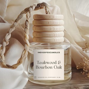 Könnte beinhalten: Ein klarer Glas-Duftöldiffusor mit Holzdeckel und geflochtener Schnur. Das Etikett lautet "Teakwood & Bourbon Oak" und "IndigoFoxCandles". Der Diffusor hat 1,8 ml.