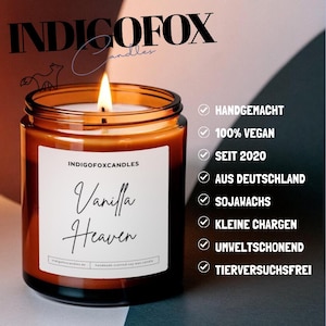 May include: A lit, brown glass jar candle with a white label that reads "Vanilla Heaven." The candle is from INDIGOFOX Candles. Additional text includes "Handmade," "100% Vegan," and "Made in Germany."