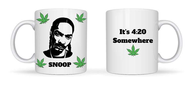 May include: White ceramic mug featuring a black silhouette of a celebrity's face, the name "SNOOP" in black, and green cannabis leaves. The other side of the mug has the text "It's 4:20 Somewhere" with a green cannabis leaf.