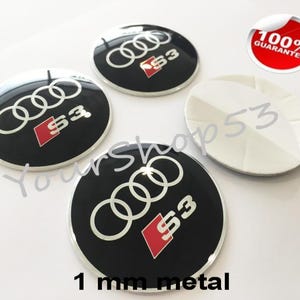May include: Four black and silver car emblems with the Audi logo and the letters "S3" in red. The emblems are 1 mm thick and made of metal.