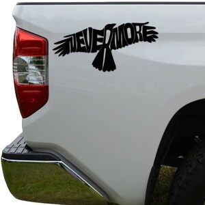 May include: Black vinyl decal of a raven with the word "NEVERMORE" incorporated into the design. The decal is applied to the back of a white pickup truck.