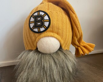 May include: A yellow gnome with a black and white Boston Bruins logo on its hat and a gray fur beard.