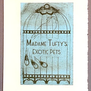 Puede incluir: Una ilustración de estilo vintage de una jaula para pájaros con el texto "Madame Tufty's Exotic Pets" impreso en la parte delantera. La jaula es azul con detalles negros y un pájaro en su interior.