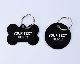 May include: Two black pet ID tags with silver key rings. One tag is bone-shaped, the other is round. Both tags have the text "YOUR TEXT HERE!" in white.