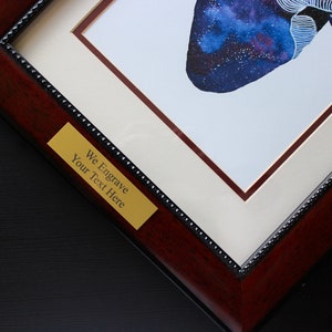 K&ouml;nnte beinhalten: Nahaufnahme eines gerahmten Drucks eines galaxief&ouml;rmigen Herzens. Der Rahmen ist aus dunklem Holz mit einer goldfarbenen Plakette, auf der "We Engrave Your Text Here" steht.