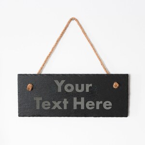 Puede incluir: Letrero de pizarra negra con un colgador de cuerda. El letrero dice "Your Text Here".