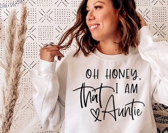 May include: A white sweatshirt with the text "Oh honey, that I am Auntie" in black lettering with a heart symbol.