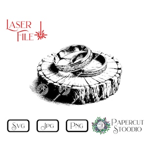 May include: Two silver rings with intricate designs are stacked on a wooden stump. The rings are on a white background.