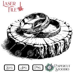 May include: Black and white line art illustration of three wedding bands on a tree stump. The bands are stacked on top of each other and have a decorative design. The tree stump is textured and has a rough surface. The image is labeled "Laser File" and "Papercut Stoodio".