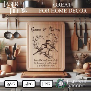 Może przedstawiać: Drewniana deska do krojenia z grawerowanymi ptakami i kwiatami, spersonalizowana imionami "Rianne & Thomas" i cytatem o miłości. Widoczny jest r&oacute;wnież tekst "LASER FILE" i "GREAT FOR HOME DECOR".