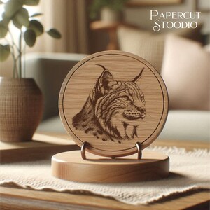 Pu&ograve; includere: Una placca circolare in legno con un'immagine incisa a laser di una lince. La placca &egrave; su un supporto in legno. Il testo "PAPERCUT STOODIO" &egrave; visibile nell'angolo in alto a destra dell'immagine.