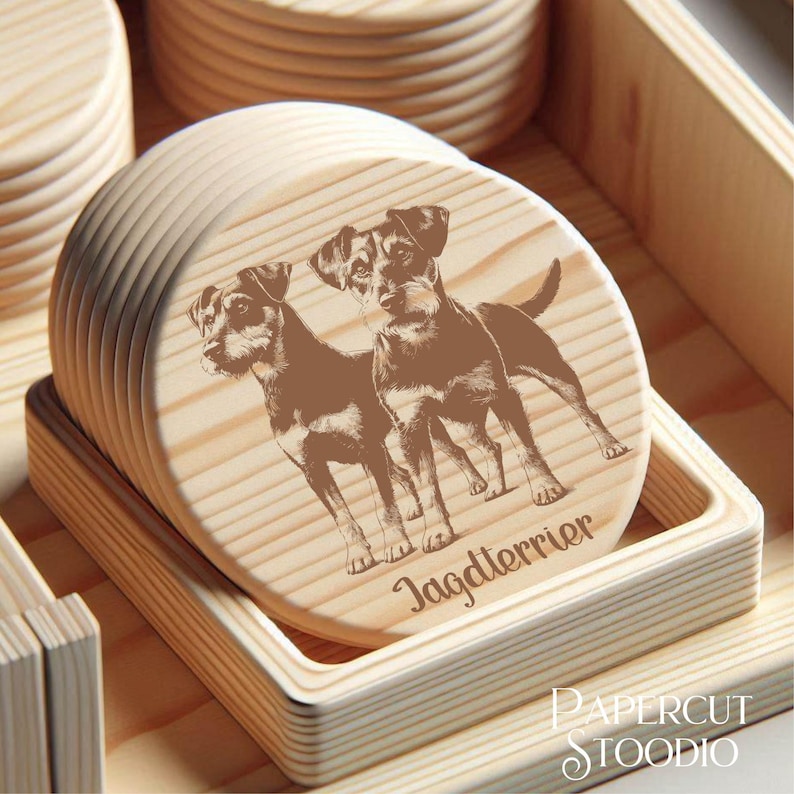 Może przedstawiać: Zestaw okrągłych drewnianych podkładek z ilustracją psa rasy Jagdterrier. Podkładki są jasnobrązowe i prezentowane w drewnianej tacy. Na podkładkach wydrukowano napis "Jagdterrier".