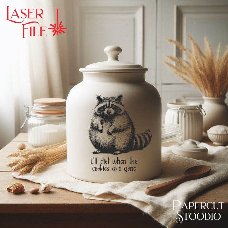May include: White ceramic cookie jar with a black and white illustration of a raccoon. The jar has the text "I'll diet when the cookies are gone" on the front.
