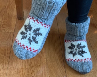 May include: A pair of gray knitted slipper socks with white and red snowflake designs.