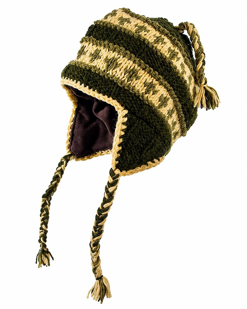 May include: A dark green and cream-colored knit earflap hat featuring a geometric pattern, a solid dark brown interior lining, and two long braided tassels hanging from the sides. The hat is constructed with thick yarn and has a textured finish.