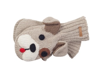 Puede incluir: Un par de mitones de punto beige con un diseño de cara de perro. El perro tiene un hocico blanco, ojos negros, una nariz marrón y una lengua roja. Los mitones tienen orejas marrones y una pequeña etiqueta.