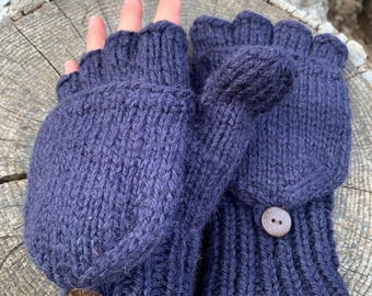 May include: A pair of dark blue fingerless gloves with a fold-over mitten flap. The gloves have a brown button on each flap and a brown leather tag with the word "AUTRY" on one glove.