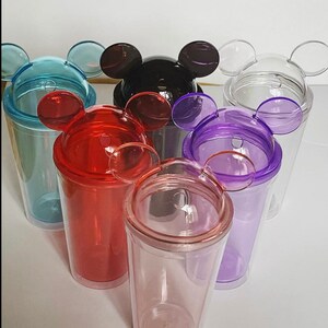 Puede incluir: Conjunto de seis vasos de pl&aacute;stico transparente con tapas de orejas de Mickey Mouse. Las tapas son de varios colores: azul, negro, transparente, rojo, morado y rosa.