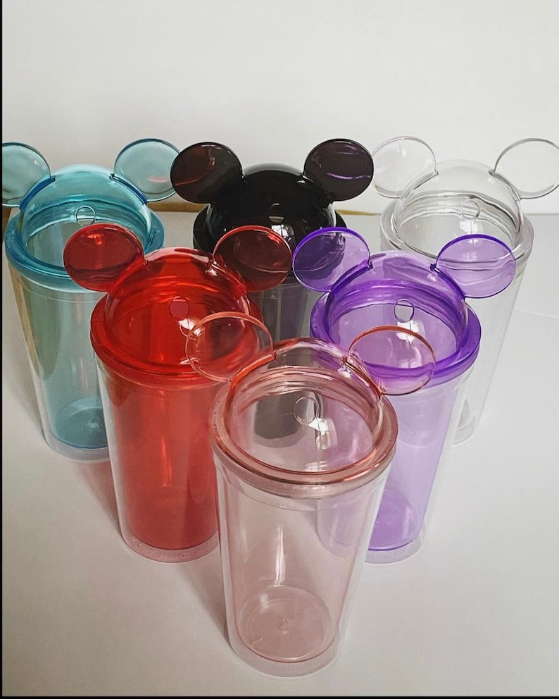 Puede incluir: Conjunto de seis vasos de pl&aacute;stico transparente con tapas de orejas de Mickey Mouse. Las tapas son de varios colores: azul, negro, transparente, rojo, morado y rosa.